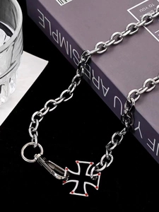 Detail of silver Cuban chain necklace with a red accent cross pendant on a book background