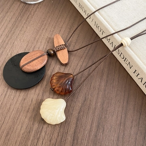 Detail of vintage wooden beads and shell pendant on a dark brown woven rope necklace