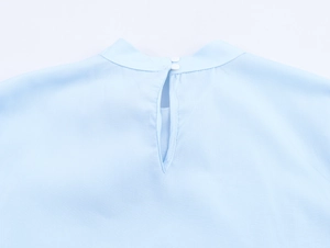 Detail view of light blue shirt showing back neckline with double buttons and keyhole cutout