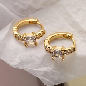 Mini gold-plated geometric huggie earrings with a square-cut zircon stone on white paper