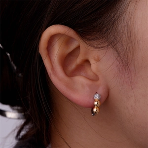 Close-up of gold beaded earrings with sparkling pave zircon stones on female model