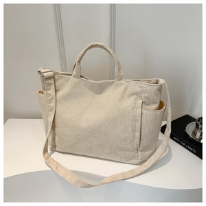 Close-up of cream corduroy tote bag showing soft ribbed texture and side storage pocket