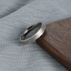 Close-up of silver stainless steel ring with engraved EKG heartbeat pattern on wood