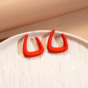 Macro detail of red matte acrylic geometric hoop earrings on a ceramic dish