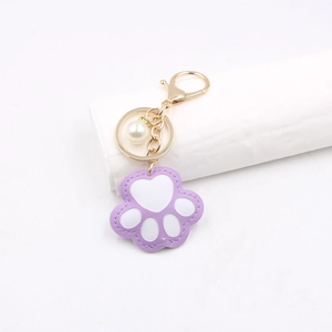 Macro shot of purple leather cat paw keychain with golden clip and pearl charm