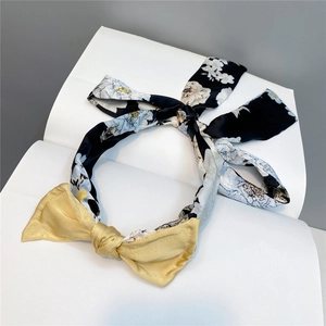 Detailed close-up of floral fabric headband with yellow satin bow on a white background