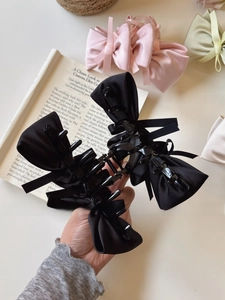 Detail of satin bow hair clips in black, pink and beige with elegant silk ribbons