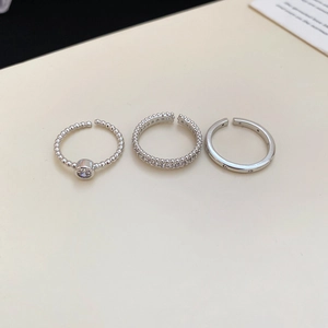 Detailed view of silver-toned metal starfish rings set with zircon stones on cream surface