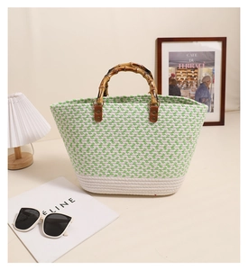 Detail of woven tote bag with green accents, bamboo handle, and chic summer accessories