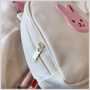 Close-up of canvas school bag featuring a pink 3D rabbit patch and smooth zipper detail