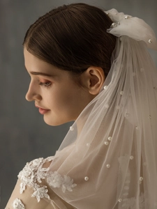 Detail of bridal short double-layer white veil with pearls and lace bow accent