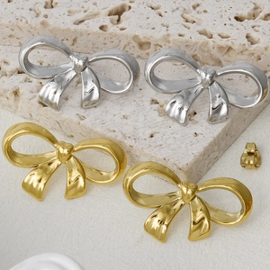 Détail de boucles d'oreilles nœud dorées et argentées sur un socle en pierre