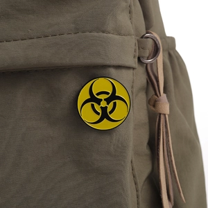 Close-up of yellow and black biohazard metal badge pinned on a green fabric bag