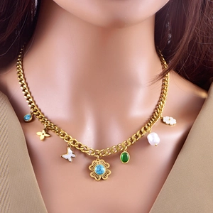 Detail of bohemian gold chain with butterfly charms, turquoise flower, and pearl pendants