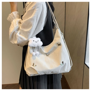 Side view of white hobo bag with silver butterfly and cloud pendant on a model