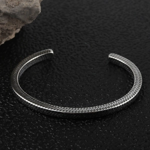 Polished silver stainless steel open bangle with textured diamond pattern on black leather