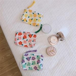Detailed view of three mini cotton floral pouches with colorful zippers and textured fabric