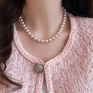 Elegant single strand round pink-purple pearl necklace shown on a tweed jacket