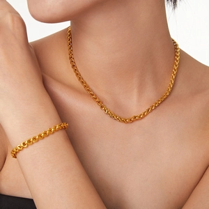 Golden geometric chain link necklace and bracelet jewelry set worn by a model