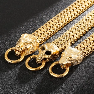 Macro shot of gold lion, skull, and wolf head charms on woven steel bracelets