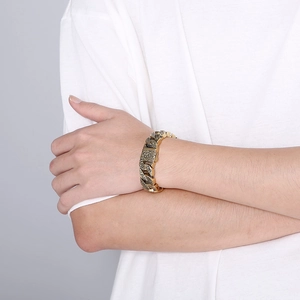 Detailed close-up of a vintage gold-toned engraved chain bracelet on a male wrist