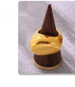 Polished 18K gold plated dome ring on dark wood cone with elegant fabric background