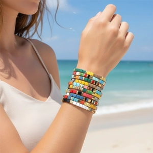 Close-up of colorful Bohemian Tila bead bracelets worn on a sunny beach background