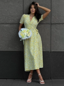Outdoor shot of a yellow wrap dress with white floral patterns and waist tie detail