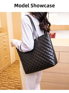Close-up of a large black quilted tote bag with classic diamond stitching worn on shoulder
