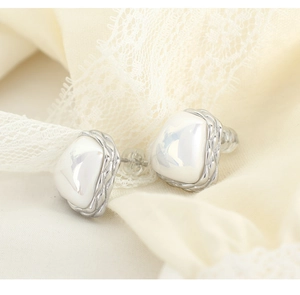 Macro shot of irregular pearl earrings with silver woven edges on soft lace fabric