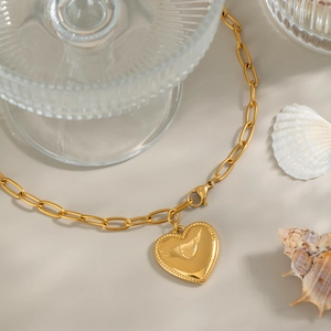 Close-up of gold heart pendant necklace on a seashell with oval link chain details