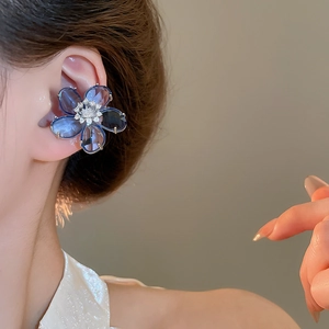 Close-up of a delicate blue crystal flower ear cuff with zircon accents on model