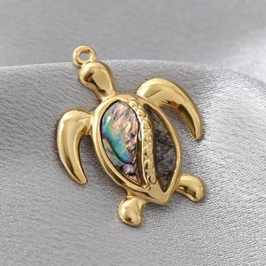 Golden turtle pendant with colorful shell inlay on grey silk background