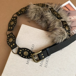 Détail de la ceinture vintage en cuir noir avec rivets en bronze et fausse fourrure grise