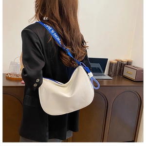 White crescent shoulder bag with a blue FASHION & BAG strap shown in a lifestyle setting