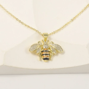 Luxurious 18k gold plated bee necklace with sparkling crystals on minimalist white stone