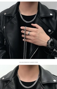 Close-up of a silver Cuban link necklace and matching braided metal ring on a model