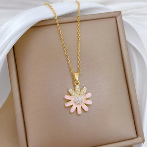 Detailed macro view of a gold daisy pendant with pink enamel petals and white zirconias