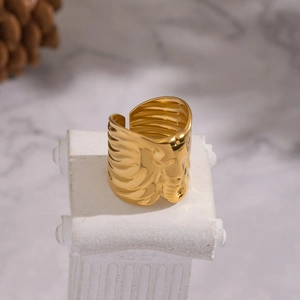 Golden wide open ring with irregular elephant texture on a white display pedestal