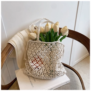 Detail of cream white hand-woven crochet bag with hollow mesh and yellow tulips