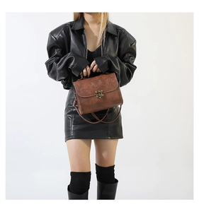 Detail of vintage brown crossbody bag with embossed floral texture and metal buckle