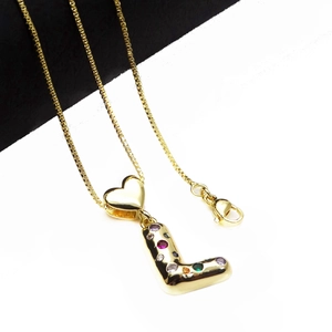 Detailed close-up of golden letter L pendant with colorful zircon stones and heart link