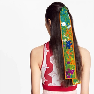 Detail of oil painting style green floral silk twilly scarf tied on a red pattern top
