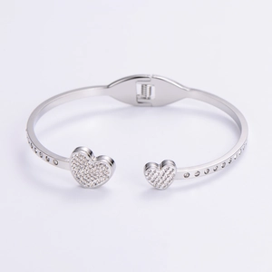 Close-up of silver open bangle featuring dual heart charms paved with sparkling zircon stones