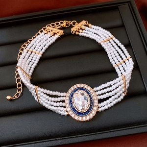 Close-up of vintage multilayer pearl necklace with blue enamel and crystal oval pendant