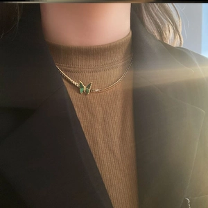 Collar vintage dorado con colgante de mariposa verde lucido por una modelo elegante