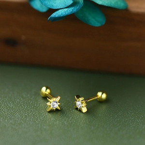 Macro view of gold star stud earring with clear zircon and screw-back on green leather