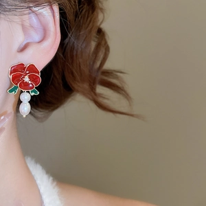 Detailed view of model wearing red rose earrings with elegant white pearl pendants