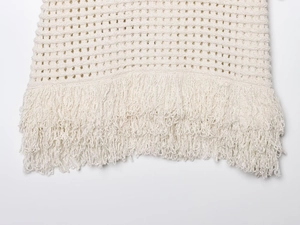 Detailed macro view of cream crochet knit texture and intricate fringe hem craftsmanship