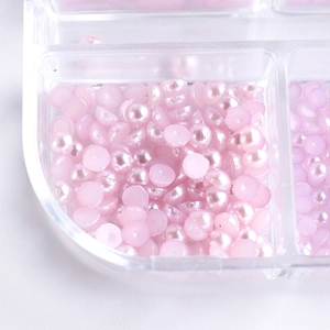 Detail of pink pearlescent half-round pearls for nail art in a clear plastic box